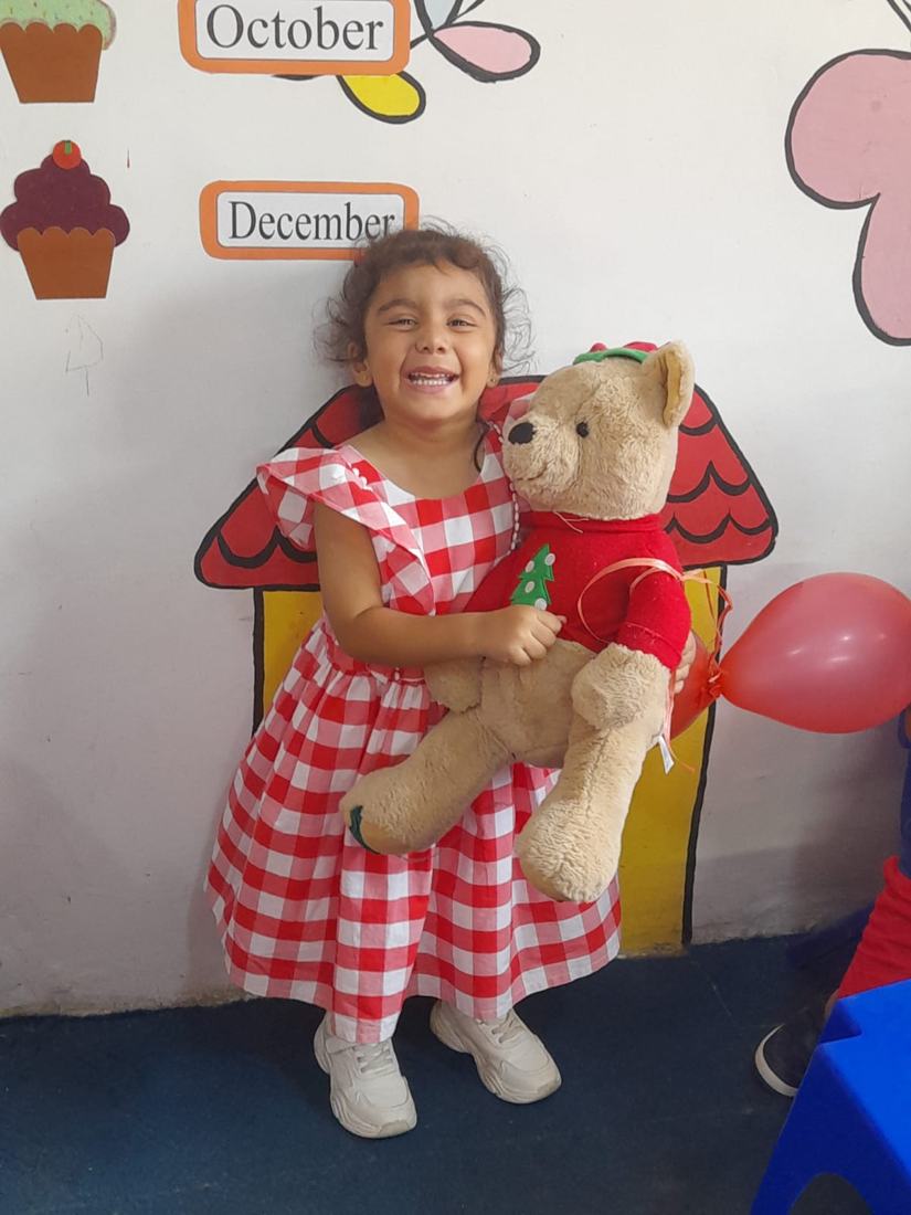A smiling child holding a teddy bear at Red Day